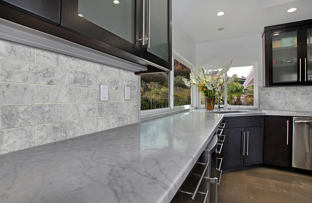 Marble subway tile backsplash with dark wood cabinets, highlighting a durable option when choosing the best backsplash tile for kitchen spaces.