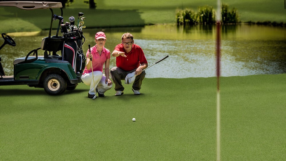 Golfers on a putting green made of commercial artificial grass, showing a hard-wearing surface for repeated usage in leisure activities.