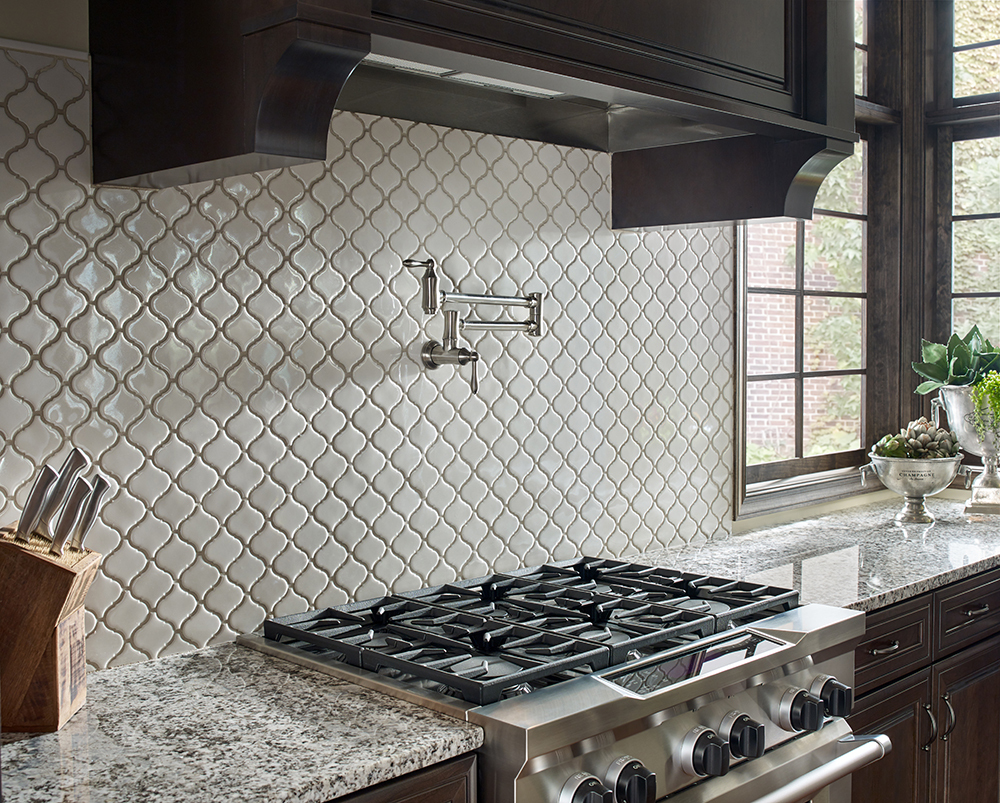 Glossy arabesque tile backsplash behind a cooktop, showcasing a decorative and easy-to-clean kitchen backsplash design.
