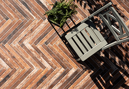 Outdoor patio with herringbone brick look porcelain tile and gray chair creating a rustic modern design